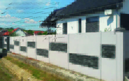 Szürke betonkerítés rózsaszín virágokkal a lábánál