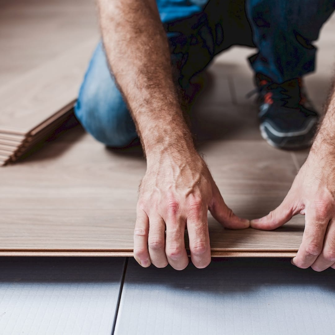 Egy parkettázó fózolt laminált padló lerakása közben Bicskén