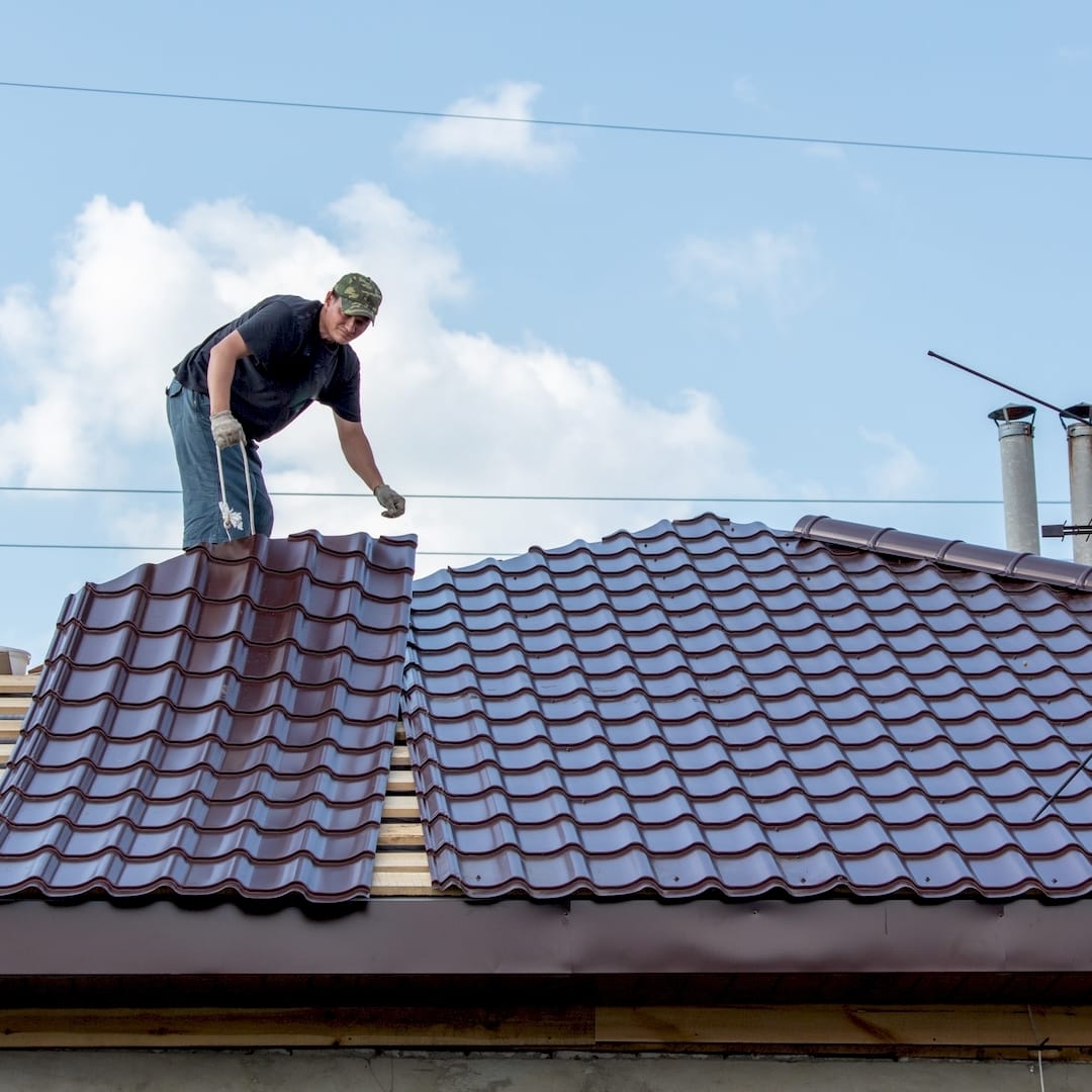 Egy tetőfedő kerámia tetőcserép javítás közben Győrben