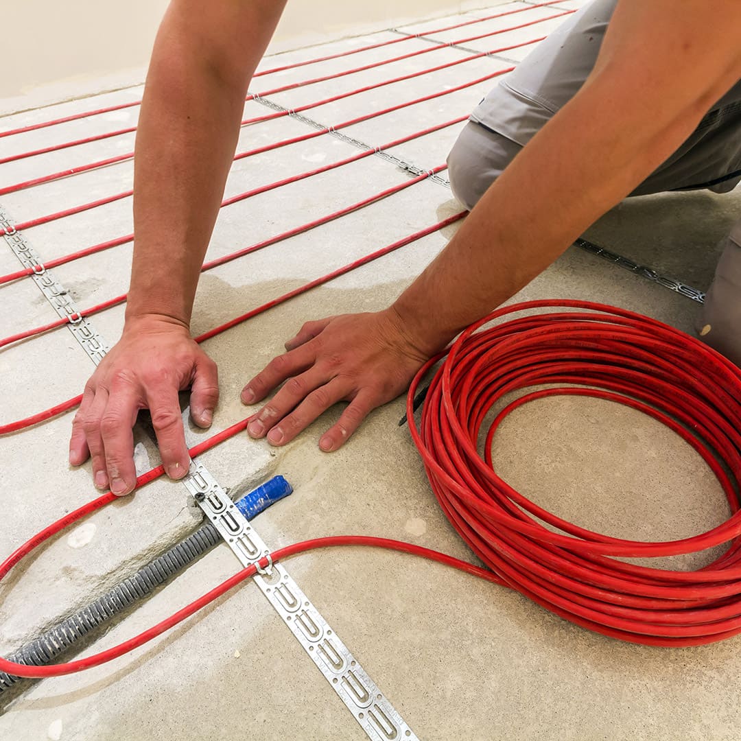 Egy villanyszerelő elektromos padlófűtés bekötése közben Győrben