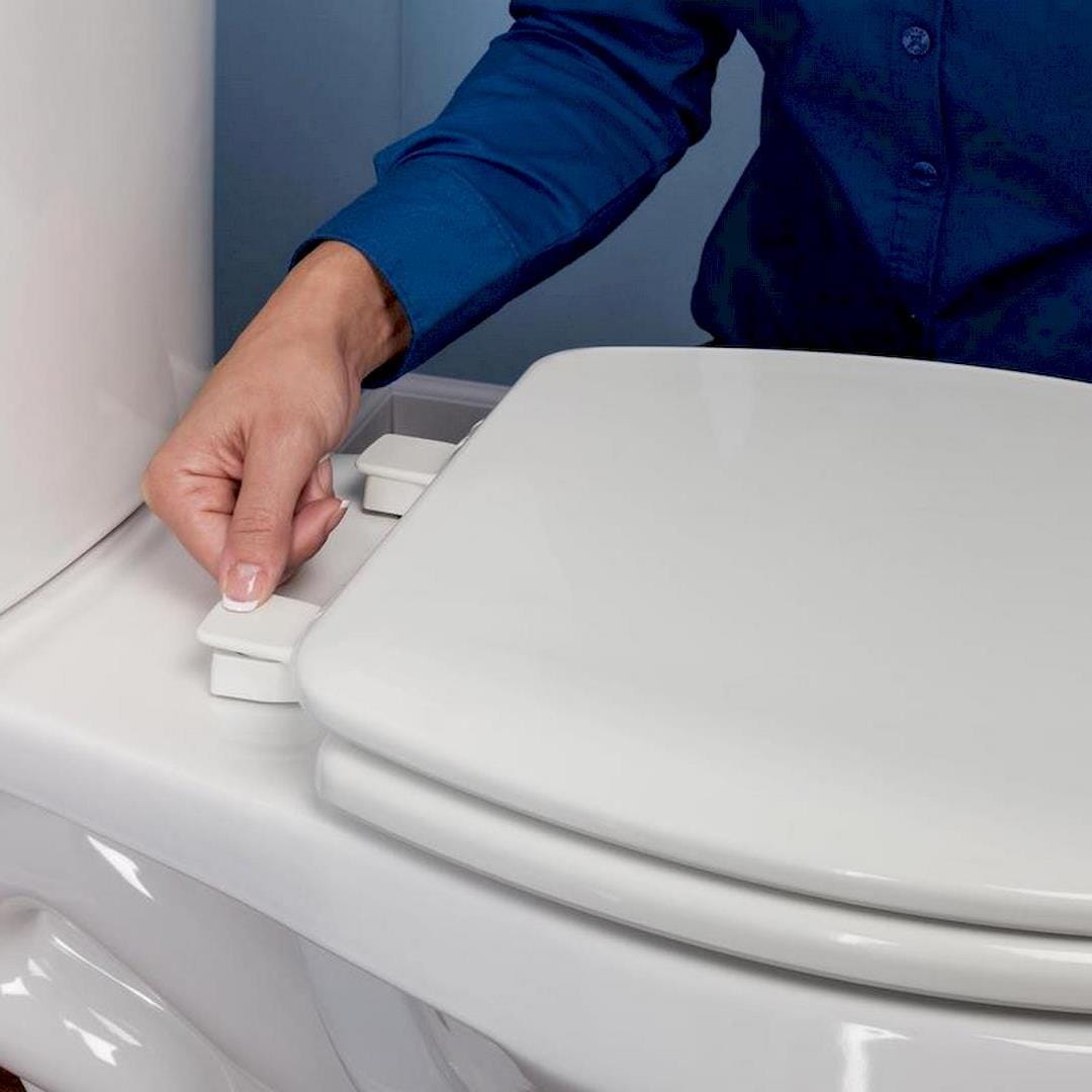 Egy wc ülőke felszerelőnek, wc ülőke felszerelése közben Bükön