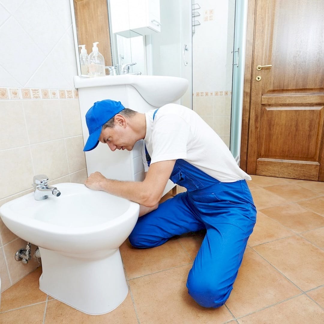 Egy szakember, wc lefolyócső szerelése közben Gödön
