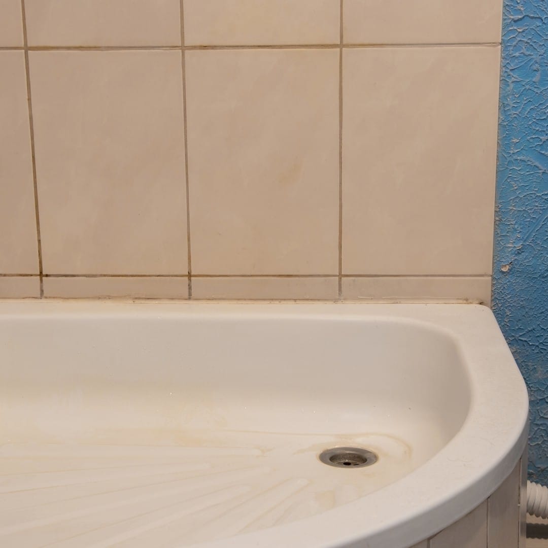 Egy vízvezeték-szerelő, zománcozott zuhanytálca beépítése közben Gödön