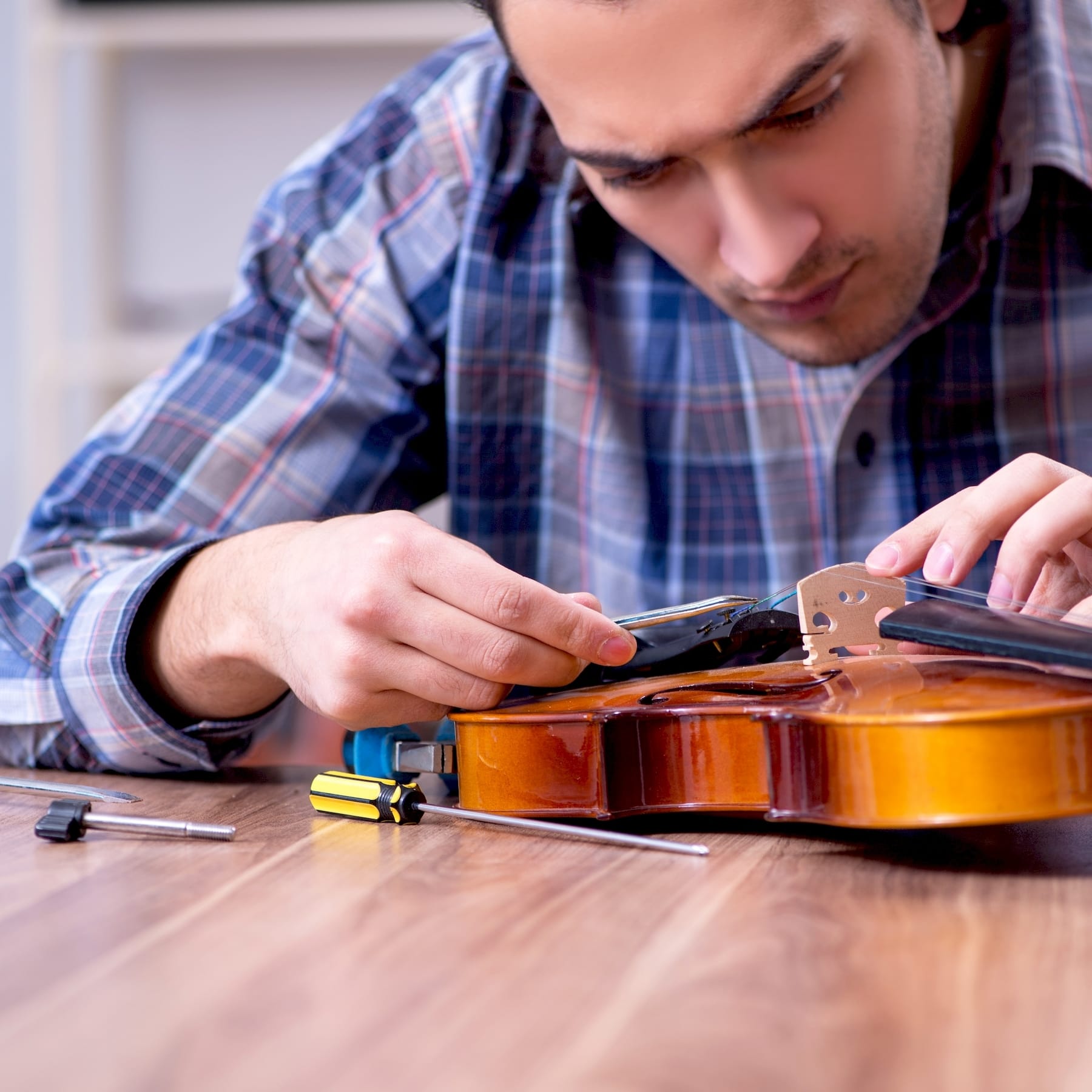 Egy hangszerjavító akusztikus gitár javítás közben Makóen