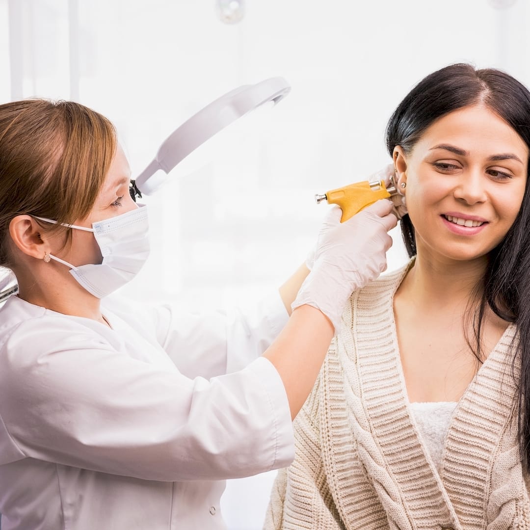 Egy piercer fülpiercing szúrás közben Nagymányoken