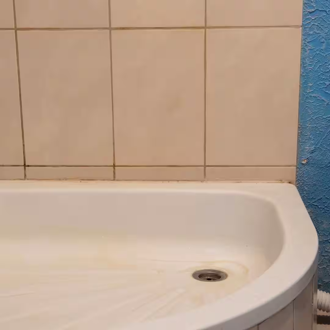 Egy vízvezeték-szerelő, zománcozott zuhanytálca beépítése közben Bonyhádon